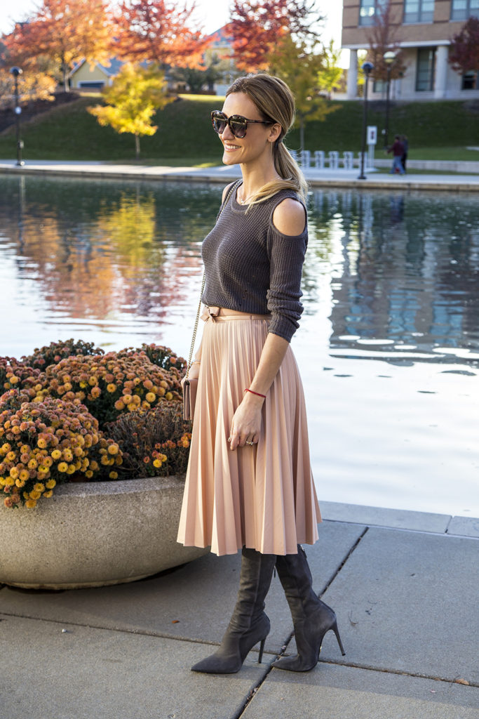 Holiday outfit ideas featured by top Indianapolis fashion blogger, Karina Style Diaries: image of a woman by the river, wearing a Zara pink Pleated Skirt, and a Free People cold shoulder sweater 