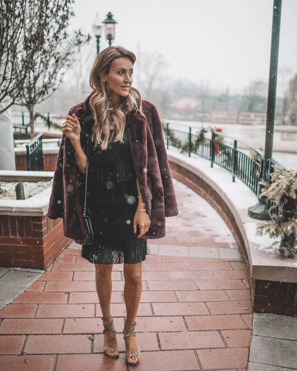 Black Fringe Dress and Fur Coat  | Holiday Party look featured by top Indianapolis fashion blogger, Karina Style Diaries: image of a woman wearing a Lesley Jane black fringe dress, Manolo Blahnik heels, Chanel bubble bag, Daniel Wellington watch and Jemma Sands drop earrings