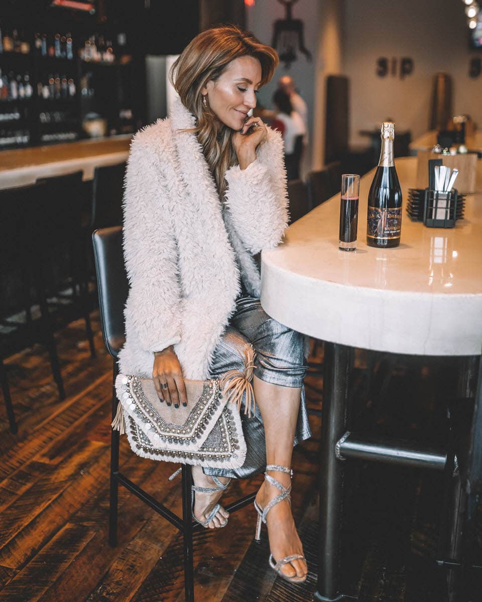 Top Indianapolis fashion blogger, Karina Style Diaries, features the perfect Holiday look with a BB Dakota metallic Jumpsuit: image of a blonde woman wearing a BB Dakota metallic jumpsuit, a BB Dakota faux fur coat, a Sashi clutch and Manolo Blahnik silver heels