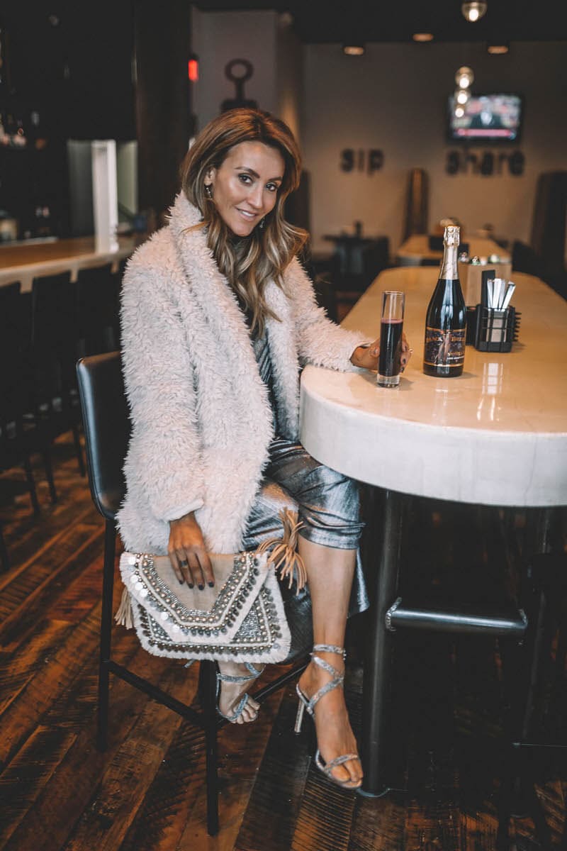 Top Indianapolis fashion blogger, Karina Style Diaries, features the perfect Holiday look with a BB Dakota metallic Jumpsuit: image of a blonde woman wearing a BB Dakota metallic jumpsuit, a BB Dakota faux fur coat, a Sashi clutch and Manolo Blahnik silver heels