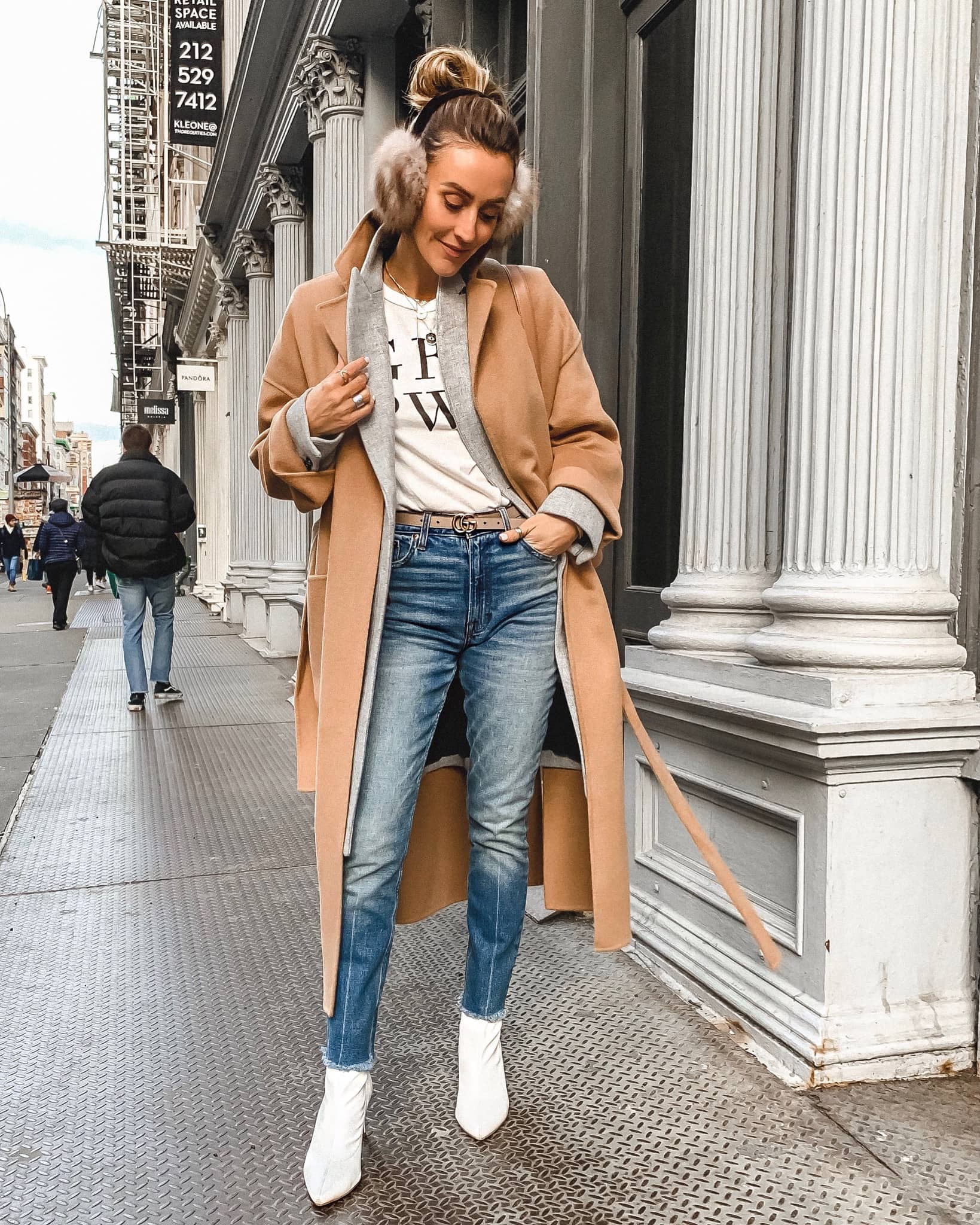 Karina Style Diaries | Girl Power Tee | High waisted jeans | white booties | camel coat | fur ear muffs | Zara camel coat styled by top US fashion blogger, Karina Style Diaries: image of a woman wearing an oversized Zara camel coat, Abercrombie and Fitch high waisted jeans, Everett graphic tee, Madewell grey coat, Gucci belt, Target white leather booties