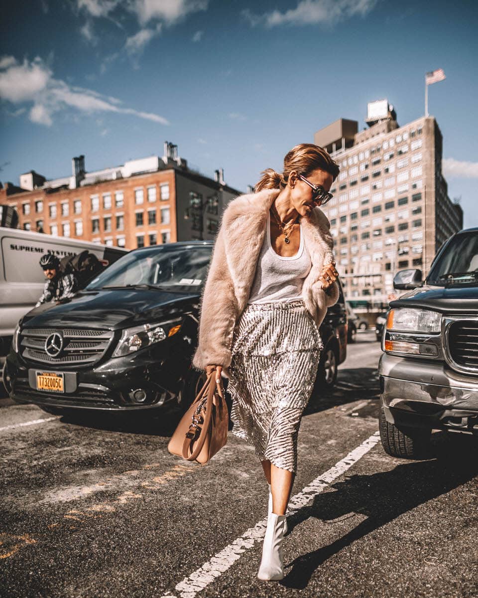 Karina Reske | NYFW spring studios | sequin skirt | fur coat | white booties | NYFW outfits and tips featured by top US fashion blogger, Karina Style Diaries: image of a woman wearing a Goodnight Macaroon sequin skirt, Madewell white tank top, a pink faux fur coat, Target white booties, Givenchy Antigona bag and Gucci sunglasses