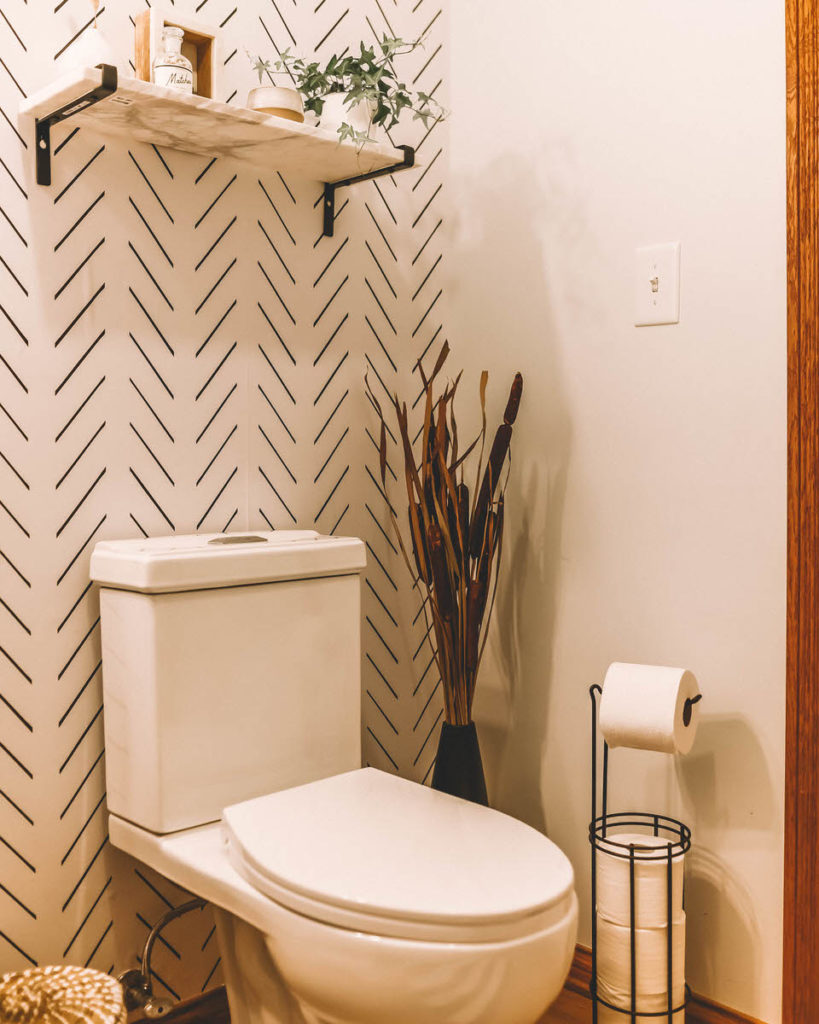 Black and white bathroom herringbone wallpaper west elm tear drop black vase marble shelf 