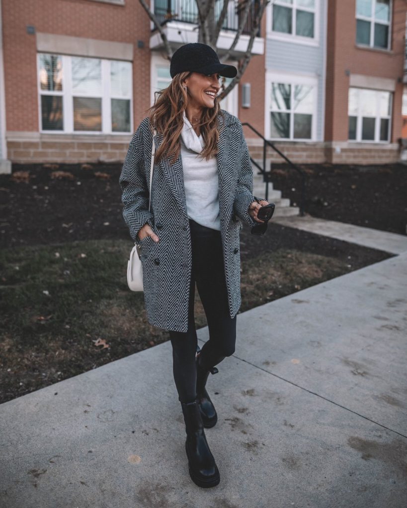 Karina wears black and white wool coat with sherpa ballcap