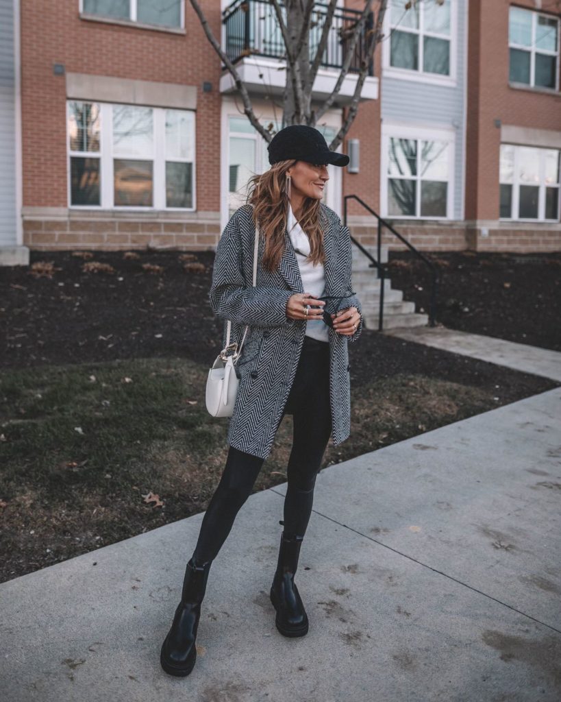 Karina wears black and white wool coat with sherpa ballcap