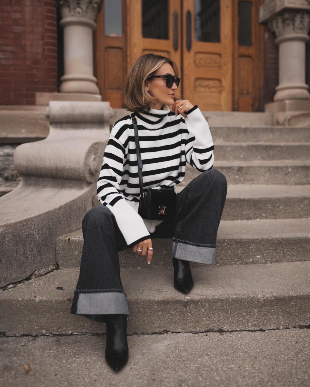 black jean outfit with striped sweater and black boots