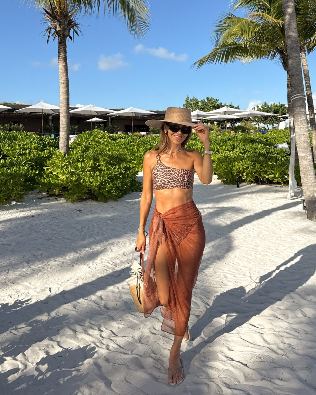 leopard print bikini with a sarong cover-up, sun hat, and sunglasses