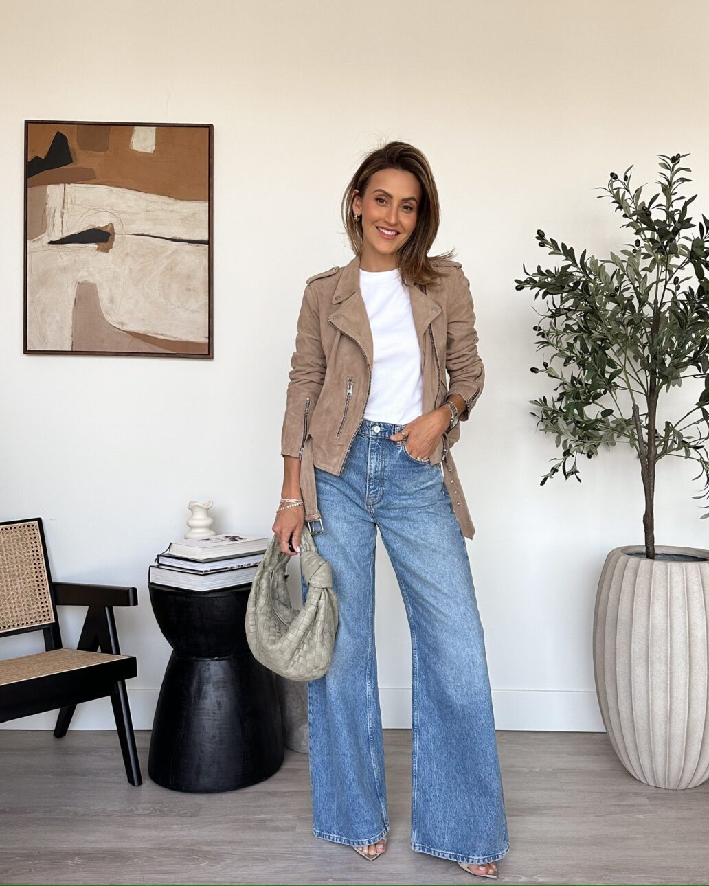 tan suede moto jacket with a white t-shirt, jeans, and heels