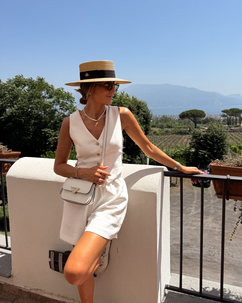 Crepe elastic waist and tie shorts with pockets, crepe vest, boater hat, Prada crossbody bag, Prada oval sunnies, Loewe flamenco XL, Miu Miu sneakers.